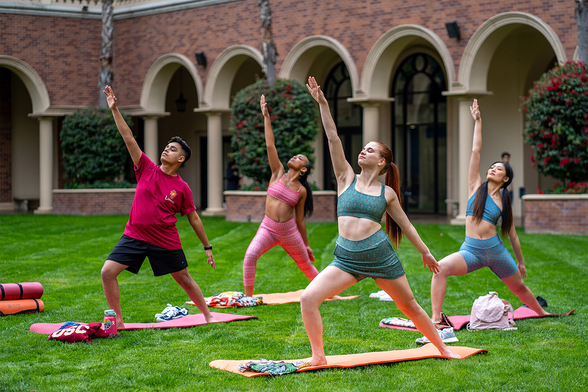 People doing yoga in a grassy courtyard